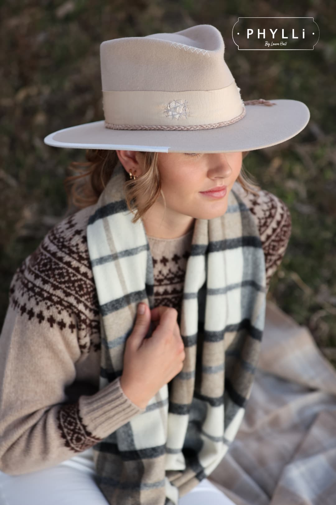 Woman wearing Fallon beige felt hat by PHYLLi Designs styled with equestrian outfit standing beside horse.