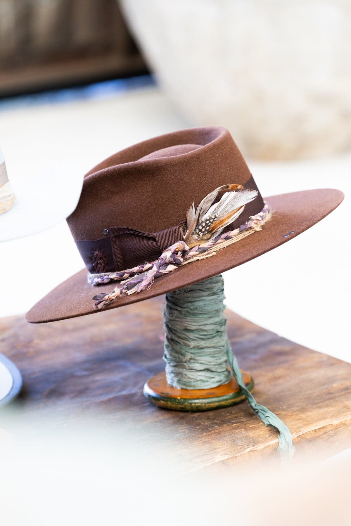 Close up detail of fallen feather bunch placed in a brown felt hat band with layered pheasant and guinea fowl feathers.