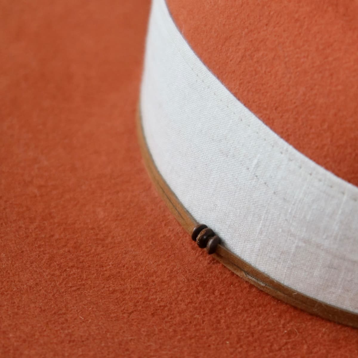 Close up detail of the Flax felt hat showing tan suede wrap with wooden bead detail.