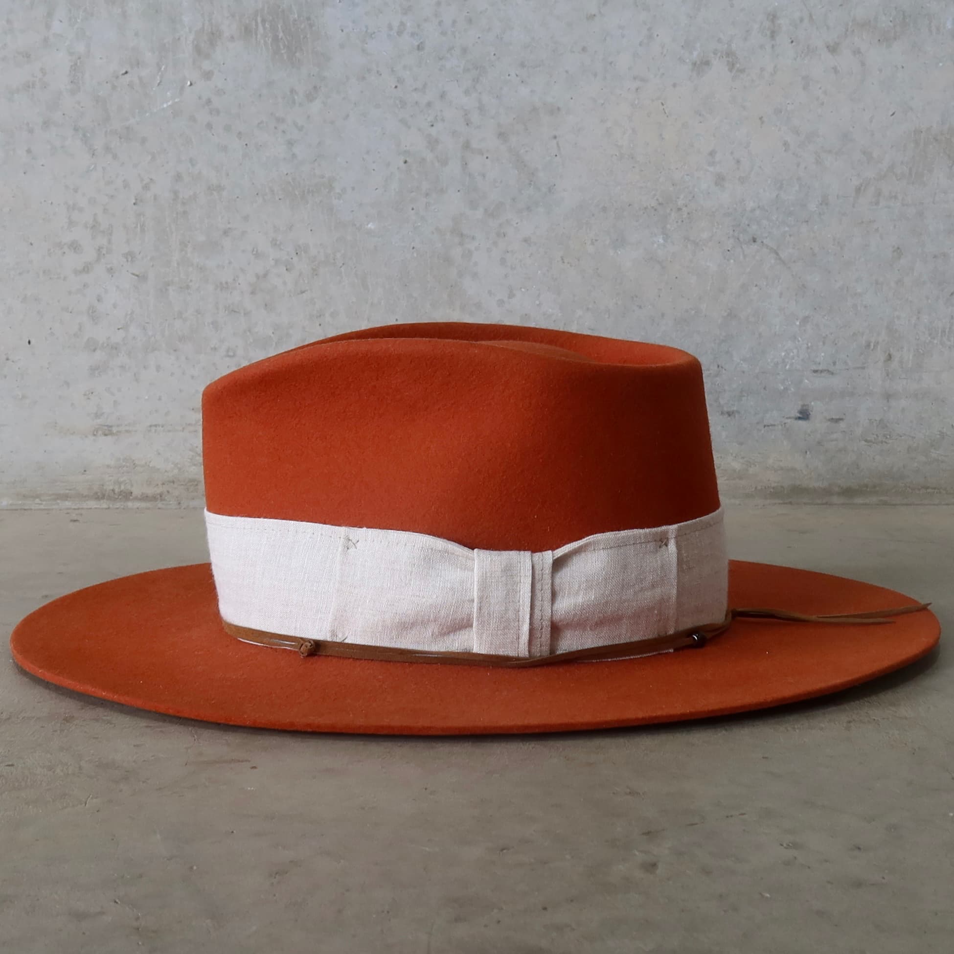 Left side view of the Spiced Pumpkin felt hat Flax by PHYLLi Designs with natural linen band and tan suede wrap.