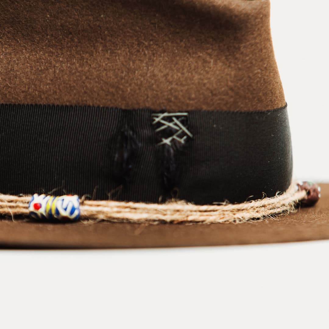 Close up detail of the Ghana felt hat showing three twine wraps finished with hand painted recycled glass beads from Ghana.