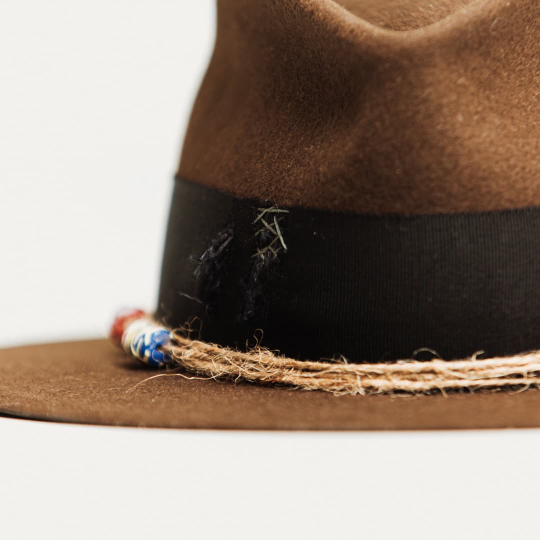 Close up detail of the Ghana felt hat showing steel grey hand-darned patches on the distressed black grosgrain band.
