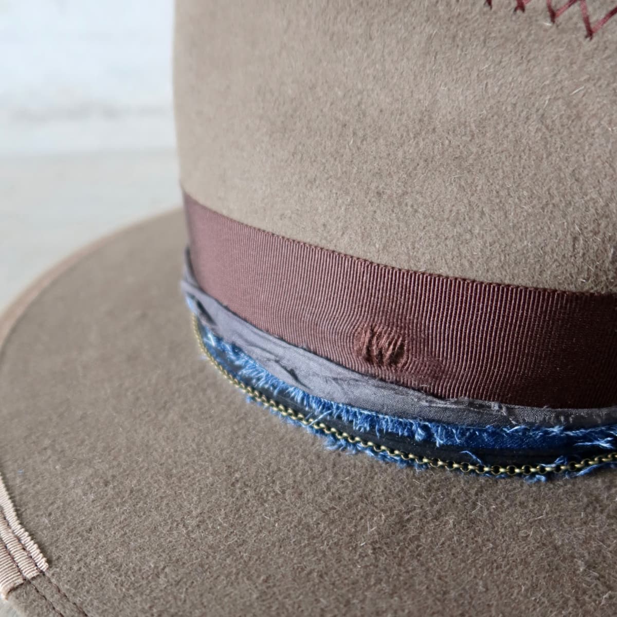 Close up detail of the Grove felt hat showing distressed dark brown Japanese grosgrain bow band with navy denim sari silk trim.