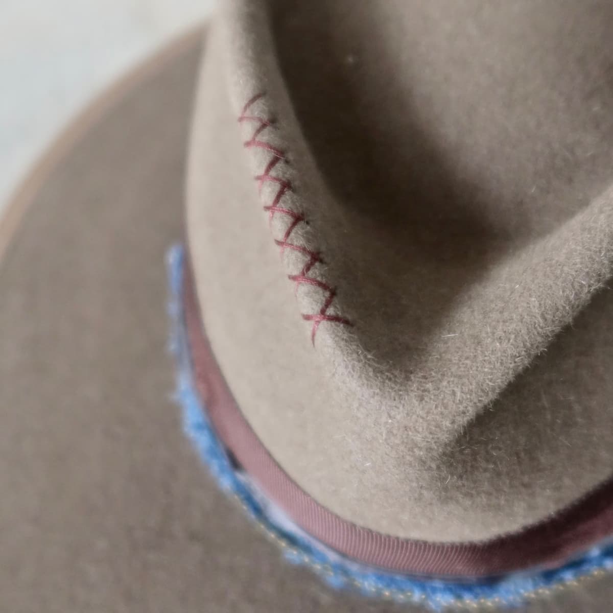 Close up detail of the Grove felt hat showing hand stitched crosses in chocolate on the felt crown.