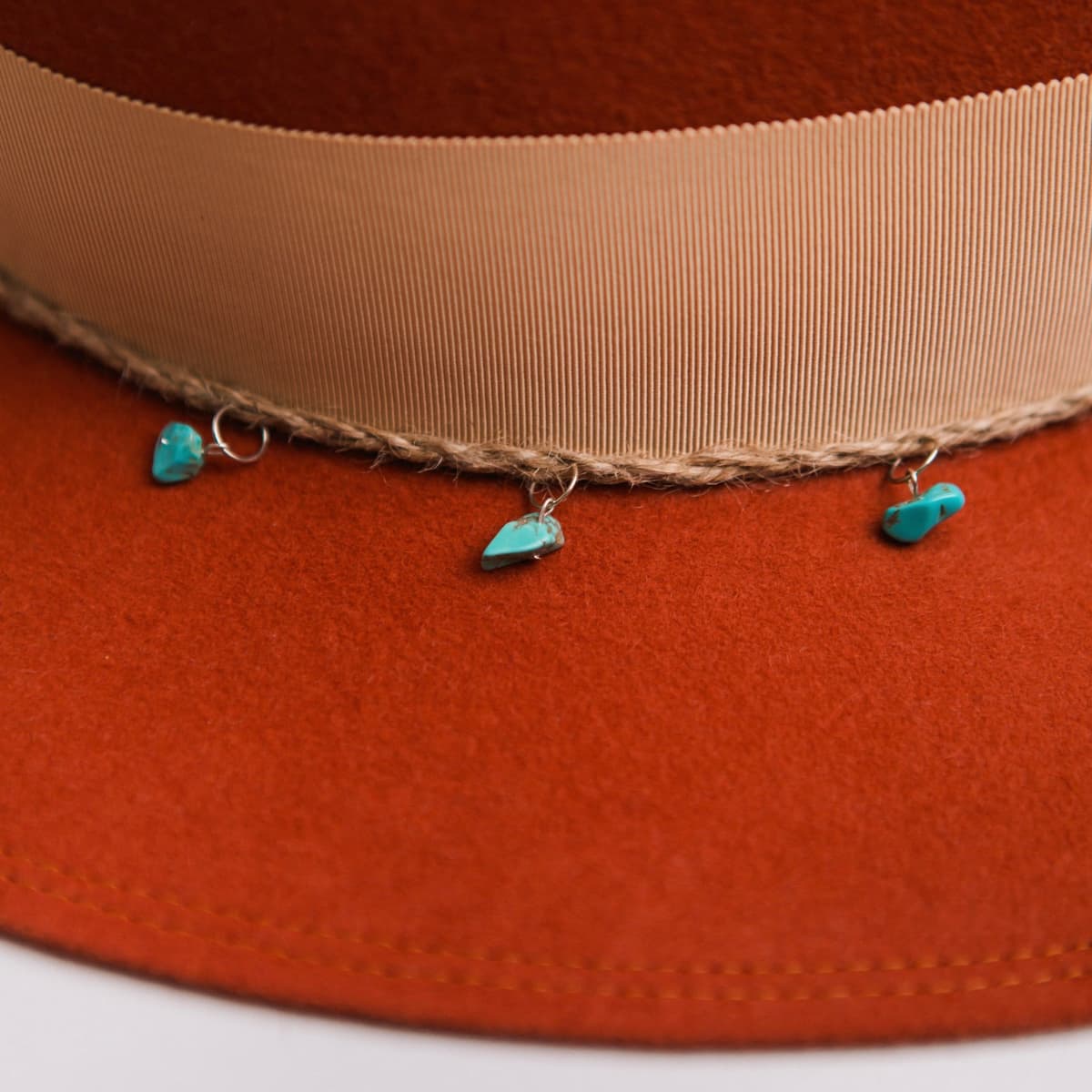 Close up detail of the Howlit felt hat showing plaited twine trim and turquoise stone charms.