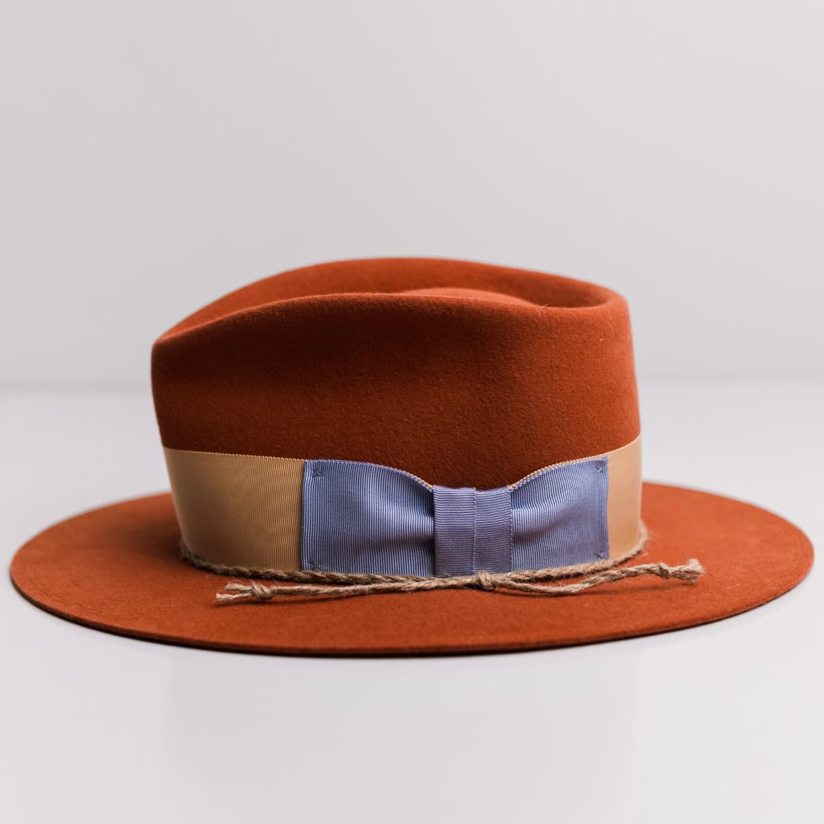 Left side view of the Howlit Spiced Pumpkin felt hat by PHYLLi Designs with plaited twine trim finished with turquoise stones.