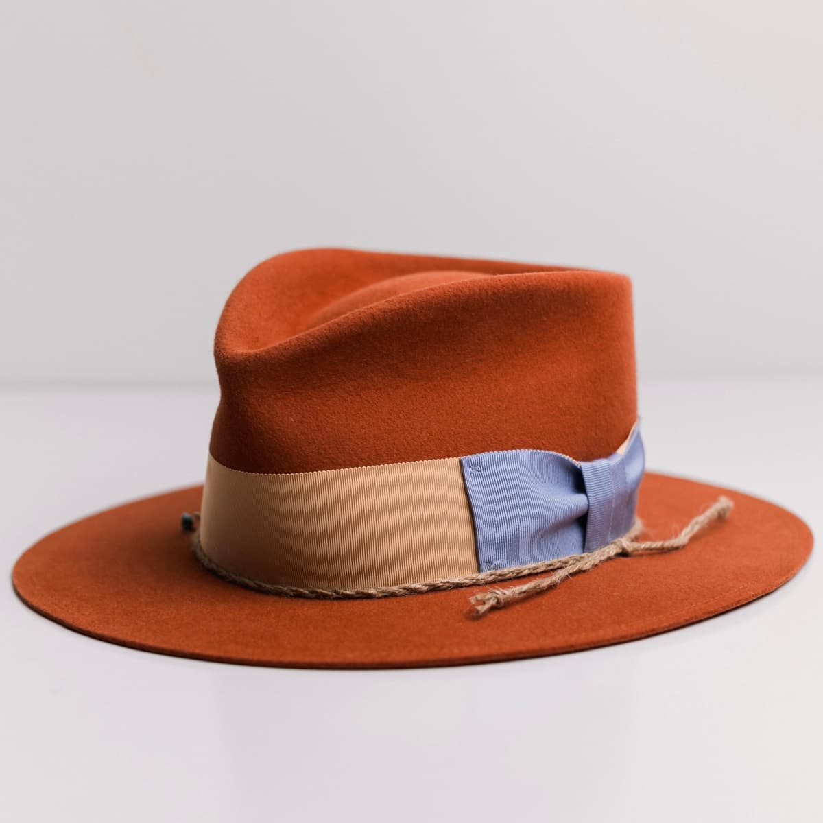 Front left angle of the Howlit Spiced Pumpkin felt hat by PHYLLi Designs with apricot grosgrain band and turquoise-detailed plaited twine.