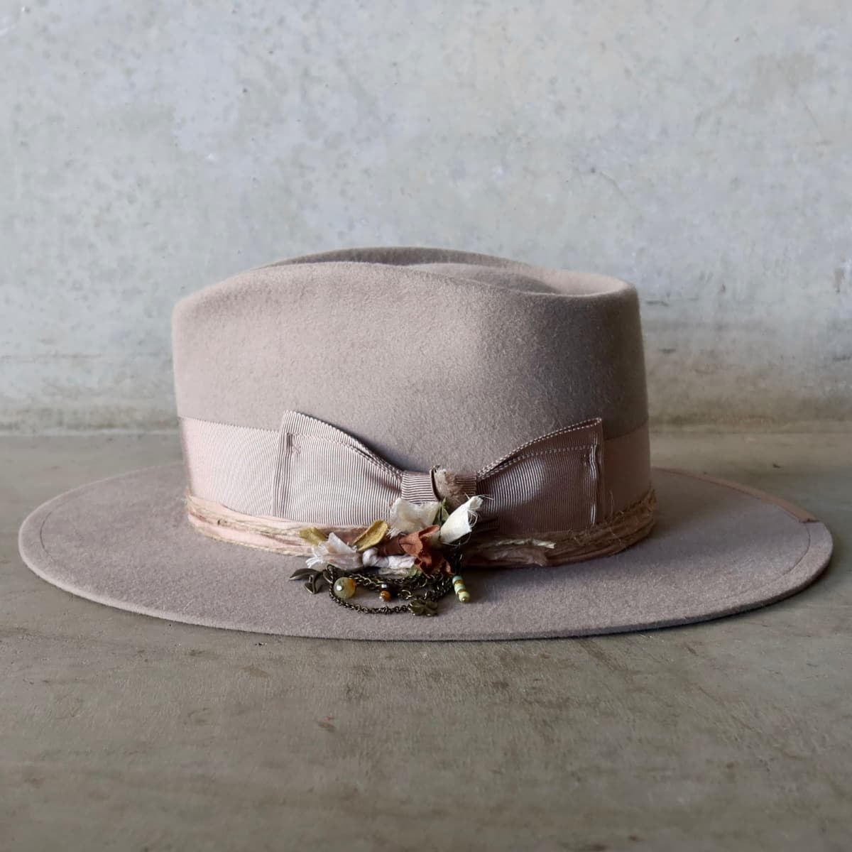 Left side view of the Sahara felt hat Huskisson by PHYLLi Designs with two twine wraps and antique bronze chunky hat pin.