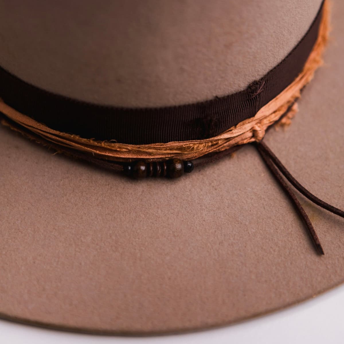 Close up detail of the Hyndman felt hat showing distressed dark brown grosgrain band and rust sari silk trim.