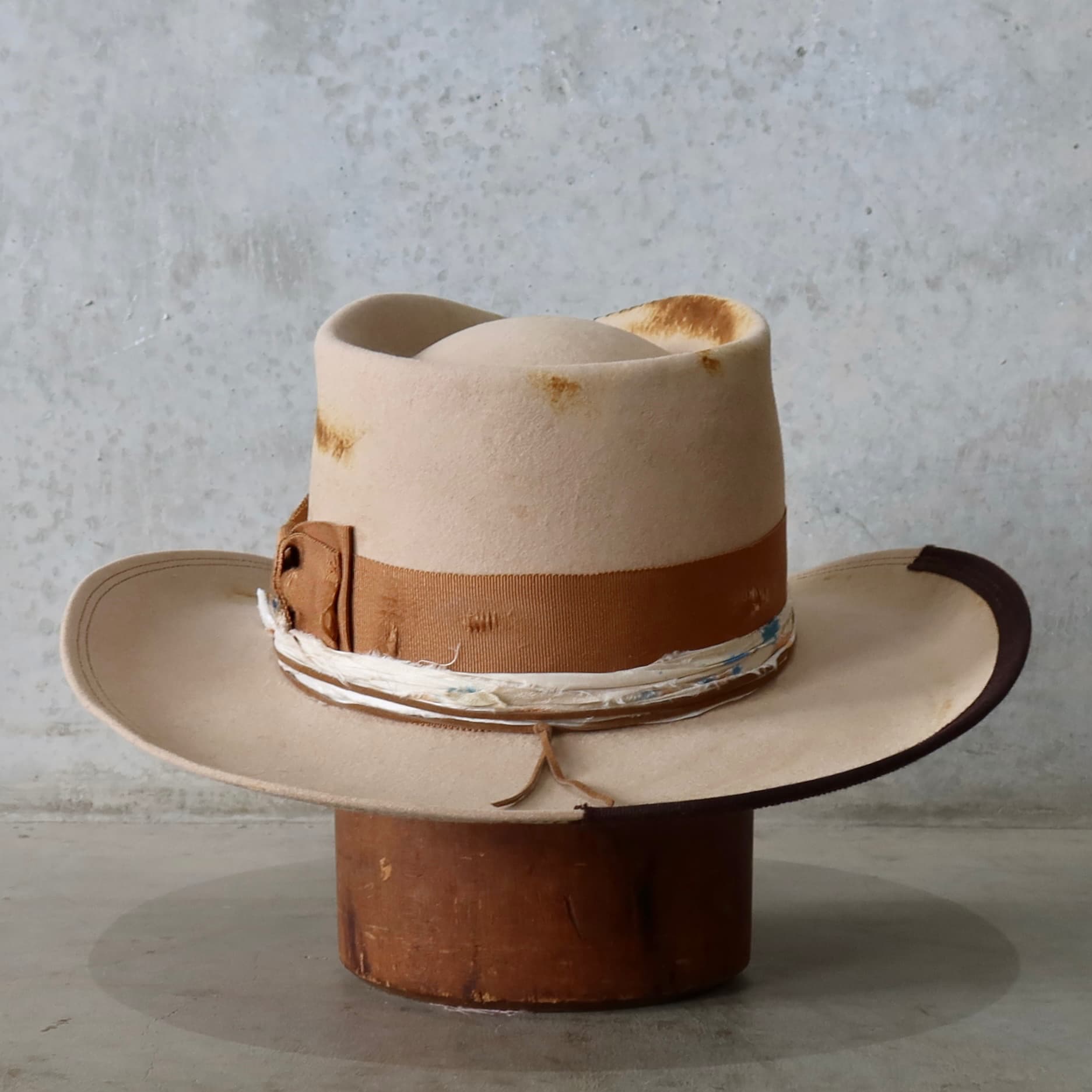 Back view of the sand cowboy hat Iluka by PHYLLi Designs featuring tan suede string and dark brown 1/3 brim trim.