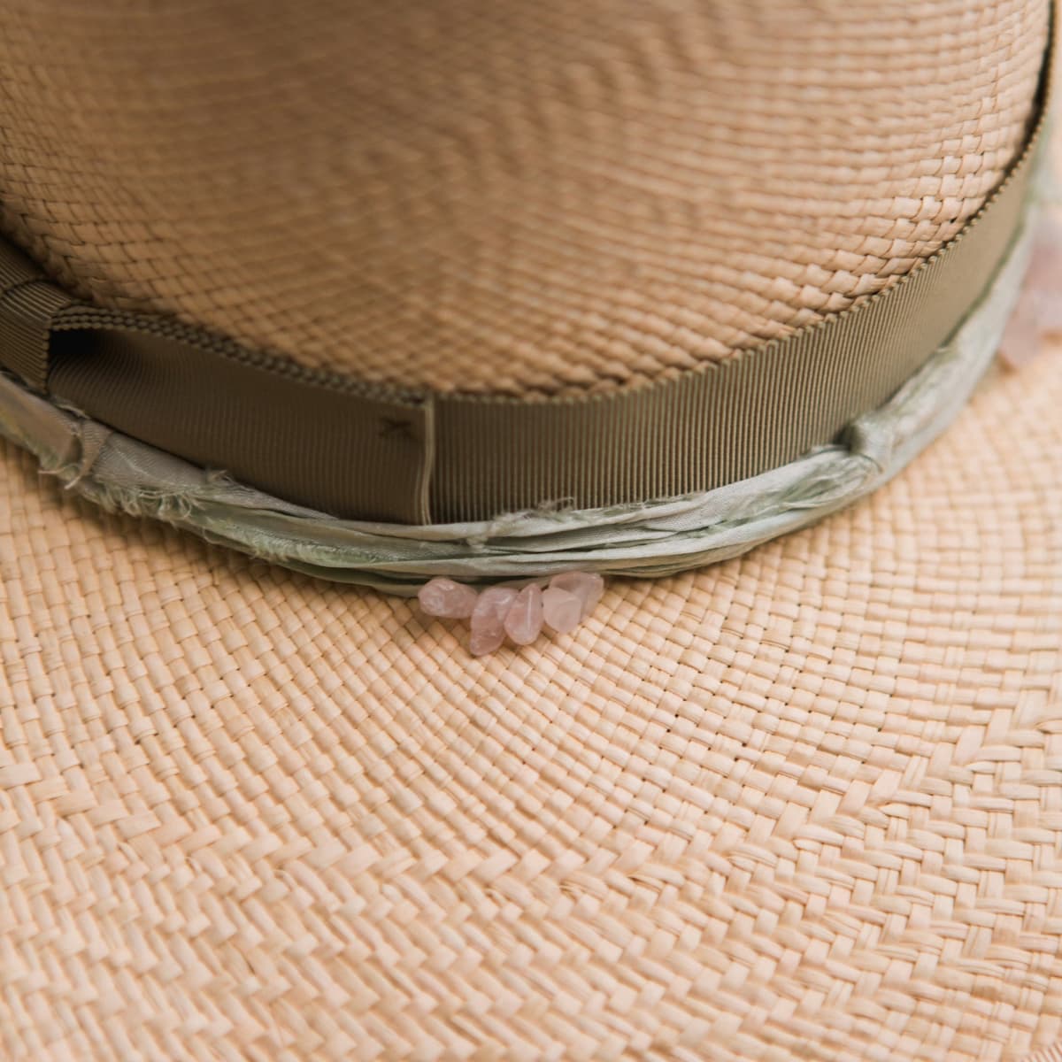 Close up detail of the Isle of Skye 2.0 Panama hat showing oil green Japanese grosgrain bow band with mint sari silk trim and rose quartz crystals.