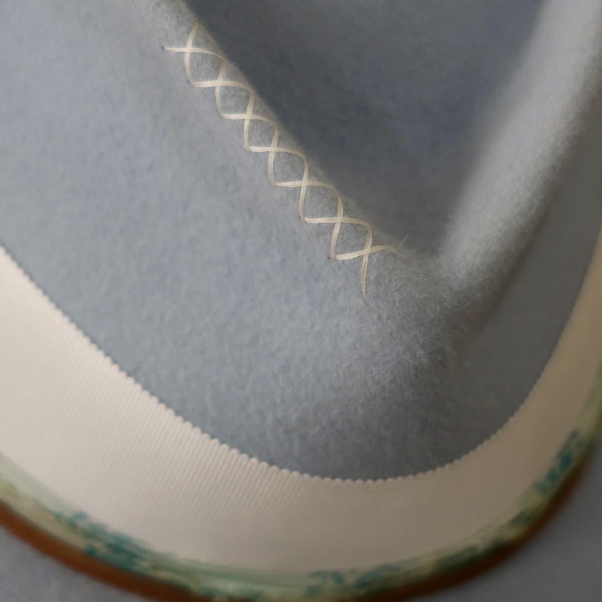 Close up detail of the Jarvis felt hat showing hand-stitched ivory crosses on the crystal blue rabbit felt crown.