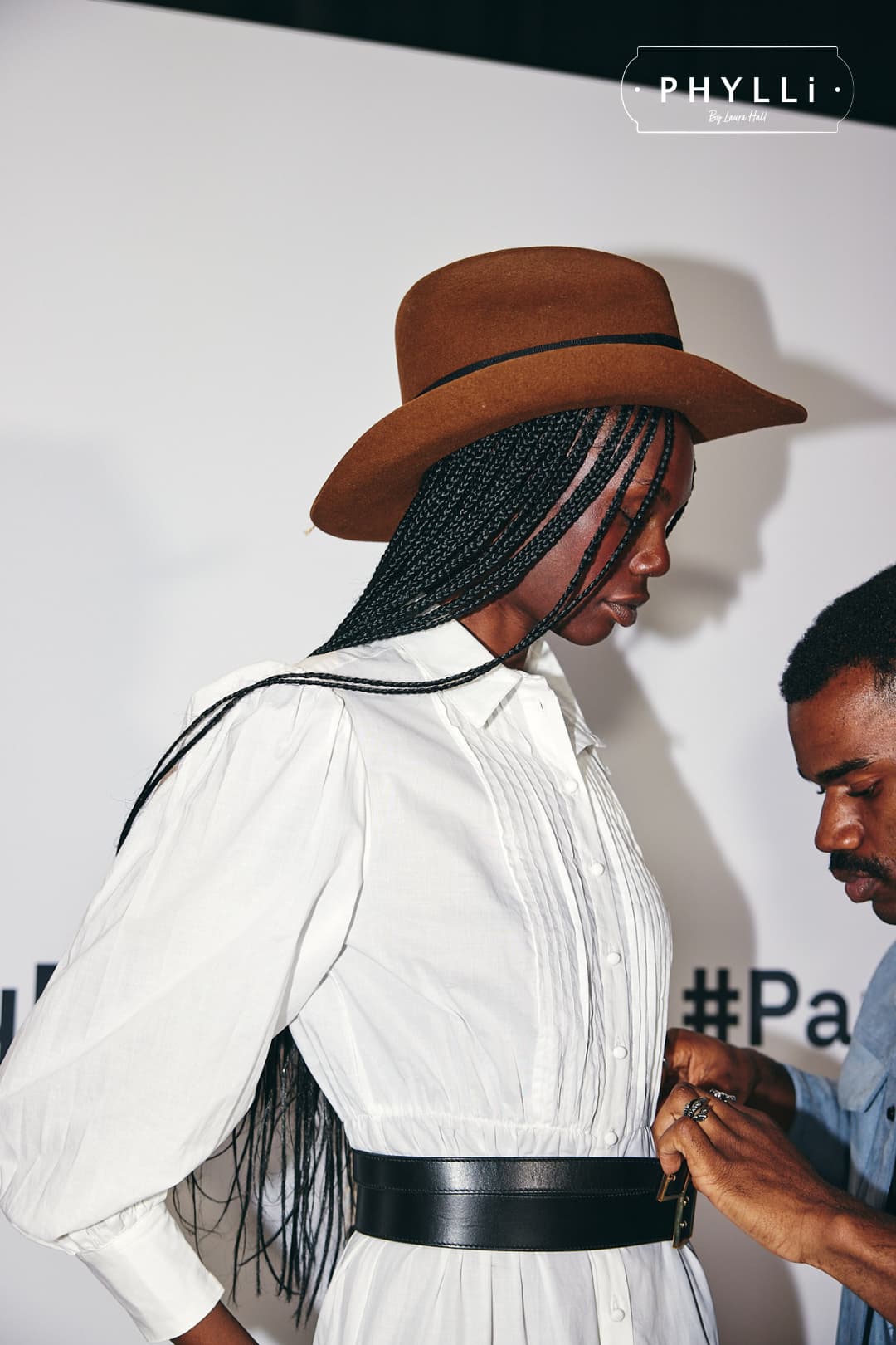 Woman wearing the Jersey caramel felt cowboy hat by PHYLLi Designs with distressed black grosgrain band backstage at a fashion event.