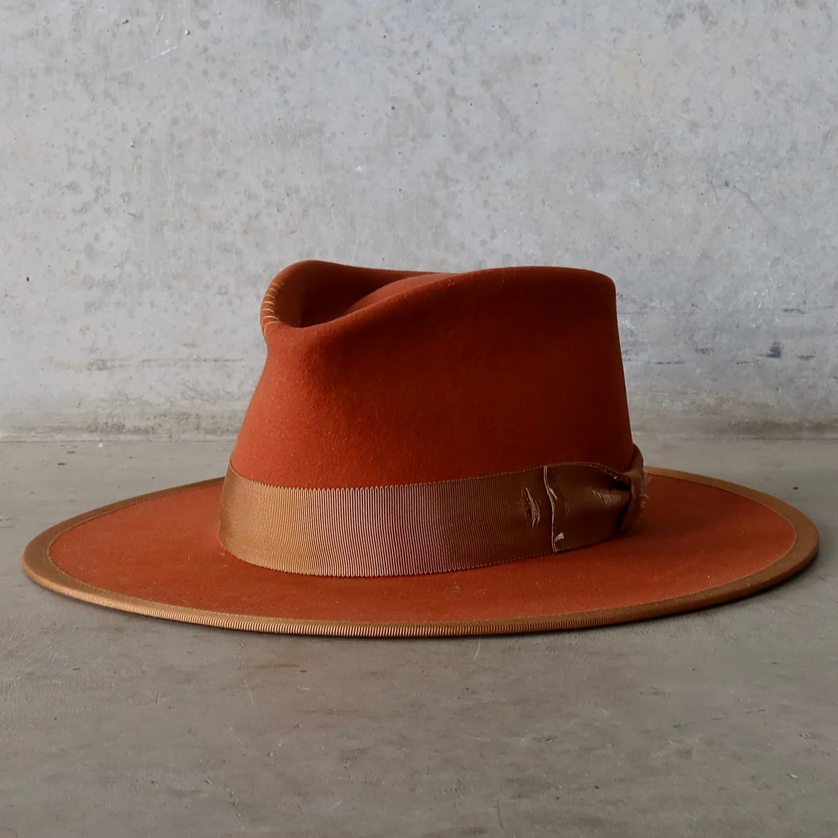 Front left angle of the Karratha Spiced Pumpkin distressed felt hat by PHYLLi Designs with copper grosgrain band and hand-stitched cross detailing.