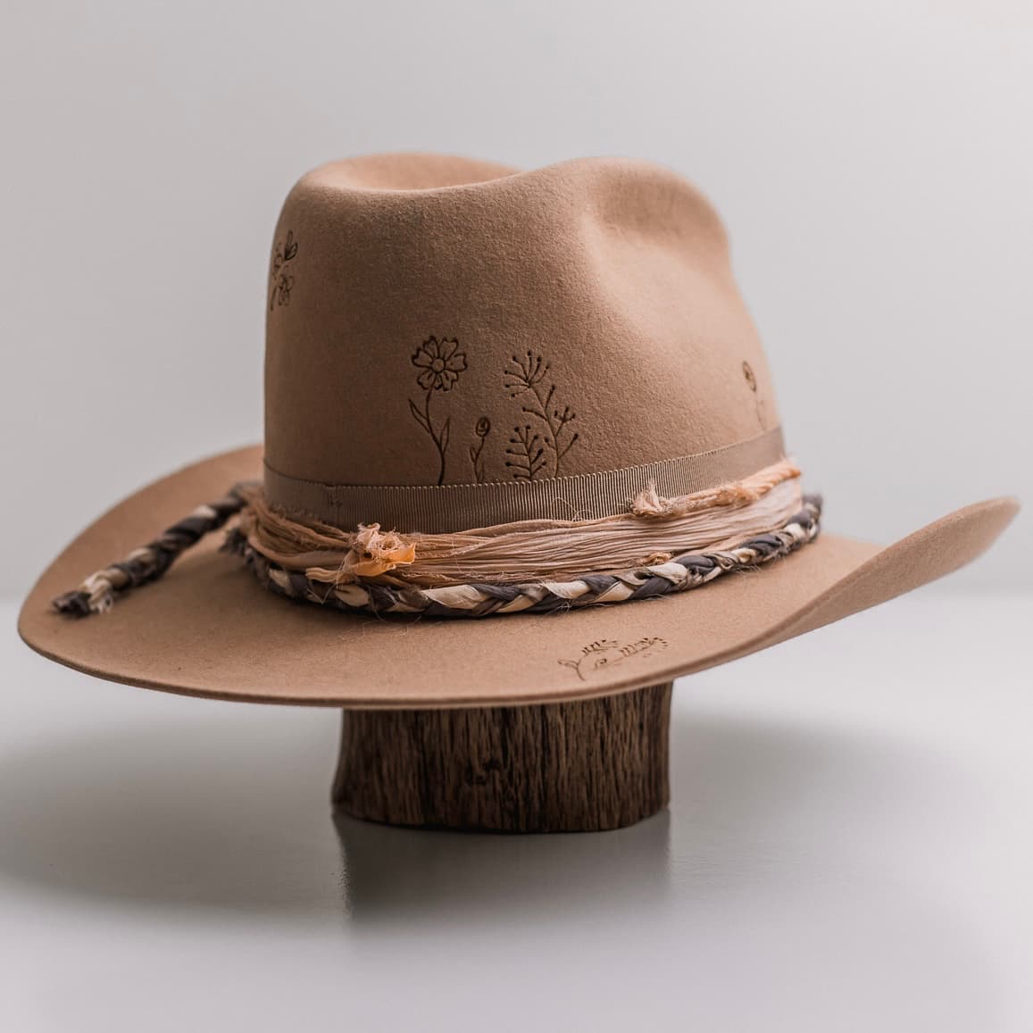 Back right angle of the camel felt cowboy hat La Fleurs by PHYLLi Designs with taupe grosgrain band and braided sari silk trim.