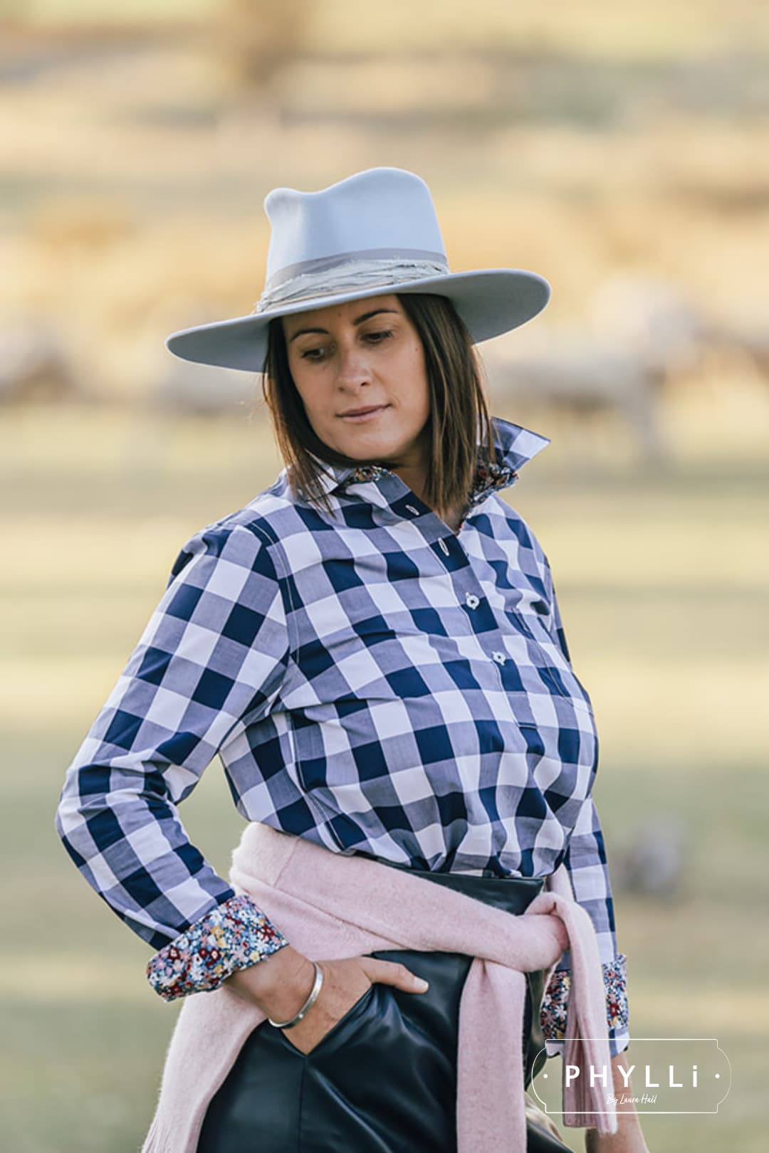 Woman wearing the La Journee Crystal Blue felt hat by PHYLLi Designs with storm sari silk trim in a natural lifestyle setting.