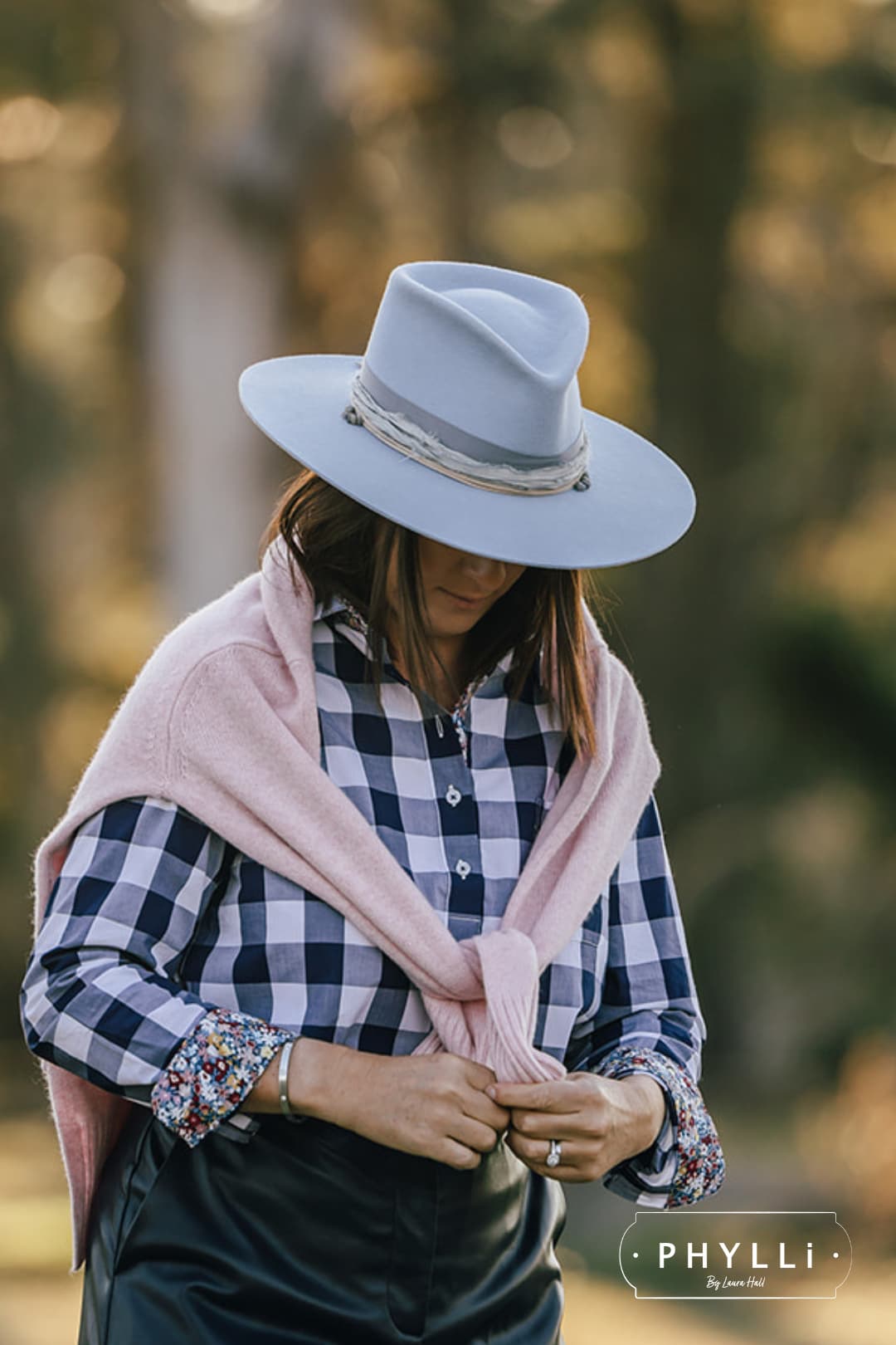 Woman wearing the La Journee Crystal Blue felt hat by PHYLLi Designs with smokey quartz crystal cluster while standing outdoors in natural light.