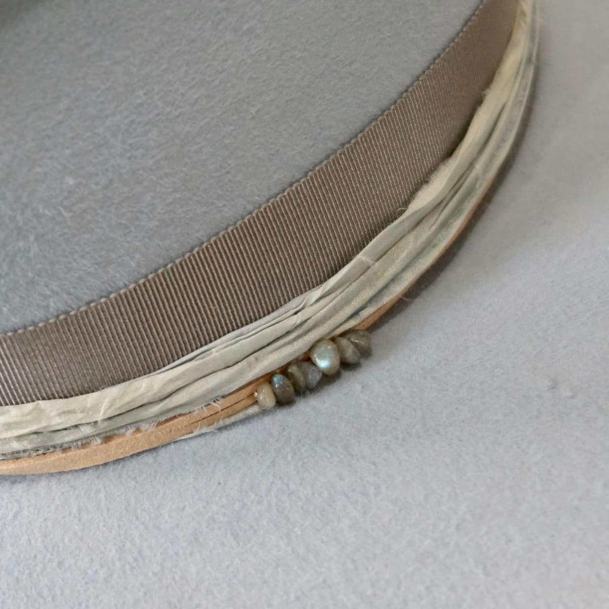Close up detail of the La Journee felt hat showing storm sari silk trimming layered beneath the cement grosgrain band.