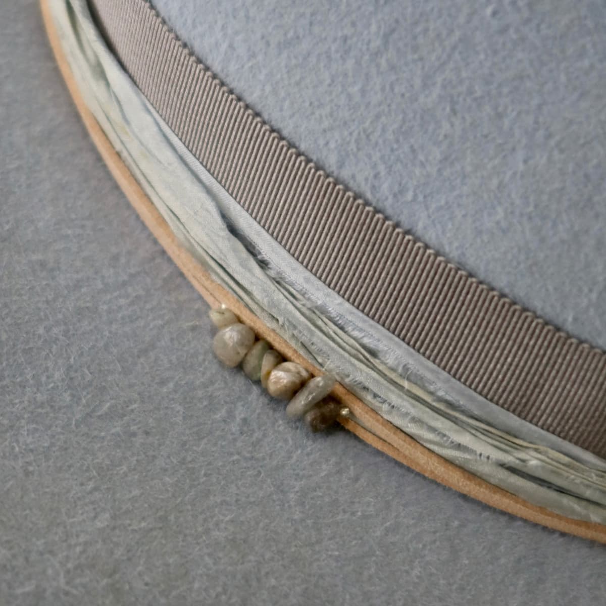 Close up detail of the La Journee felt hat showing three smokey quartz crystal cluster set into the trim.