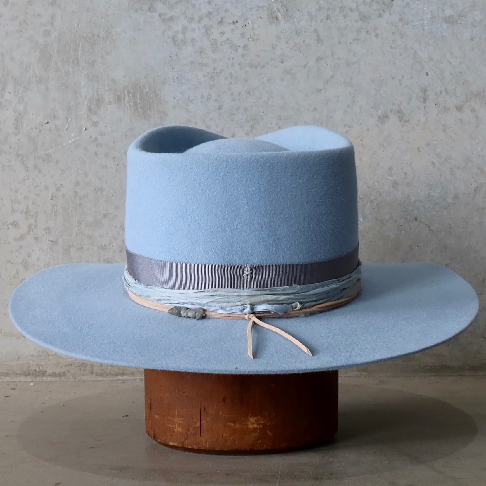 Back view of the La Journee Crystal Blue felt hat by PHYLLi Designs featuring cement Japanese grosgrain band and storm sari silk trim.