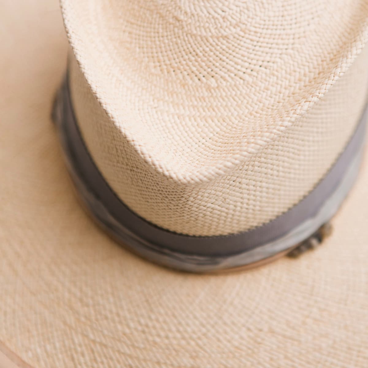 Close up detail of the La Journee Panama hat showing handwoven toquilla straw crown and cement Japanese grosgrain band.