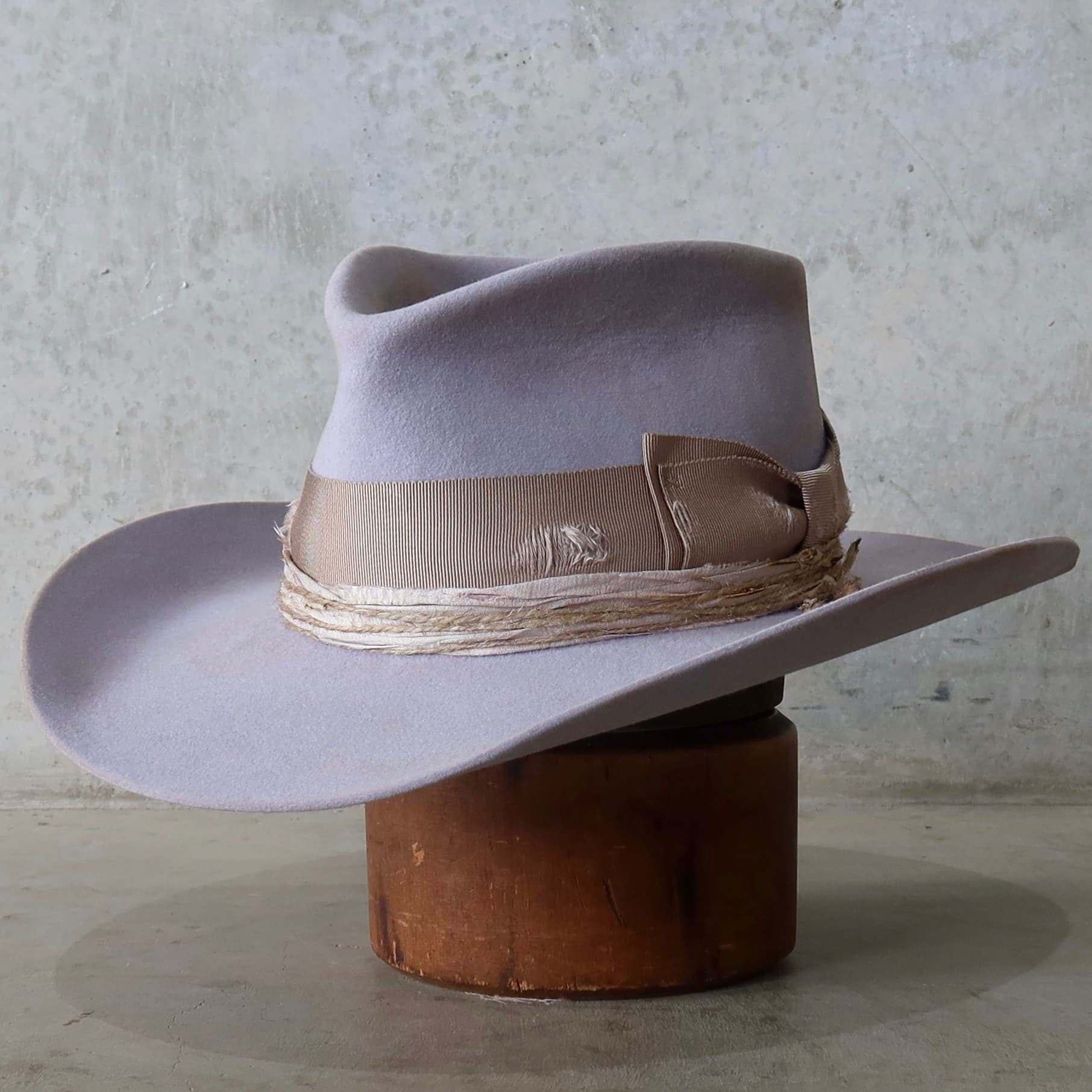 Front left angle of the lilac distressed felt cowgirl hat Lacey by PHYLLi Designs with distressed grosgrain bow band and twine wraps.