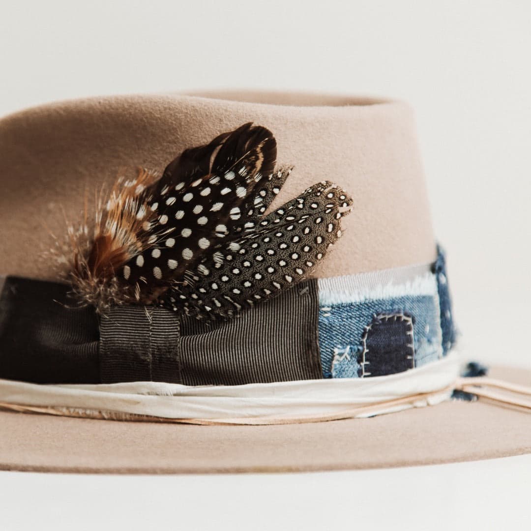 Close up detail of the Levi Limited Edition Sahara felt hat by PHYLLi Designs featuring fallen feather cluster with distressed Japanese grosgrain bow band.