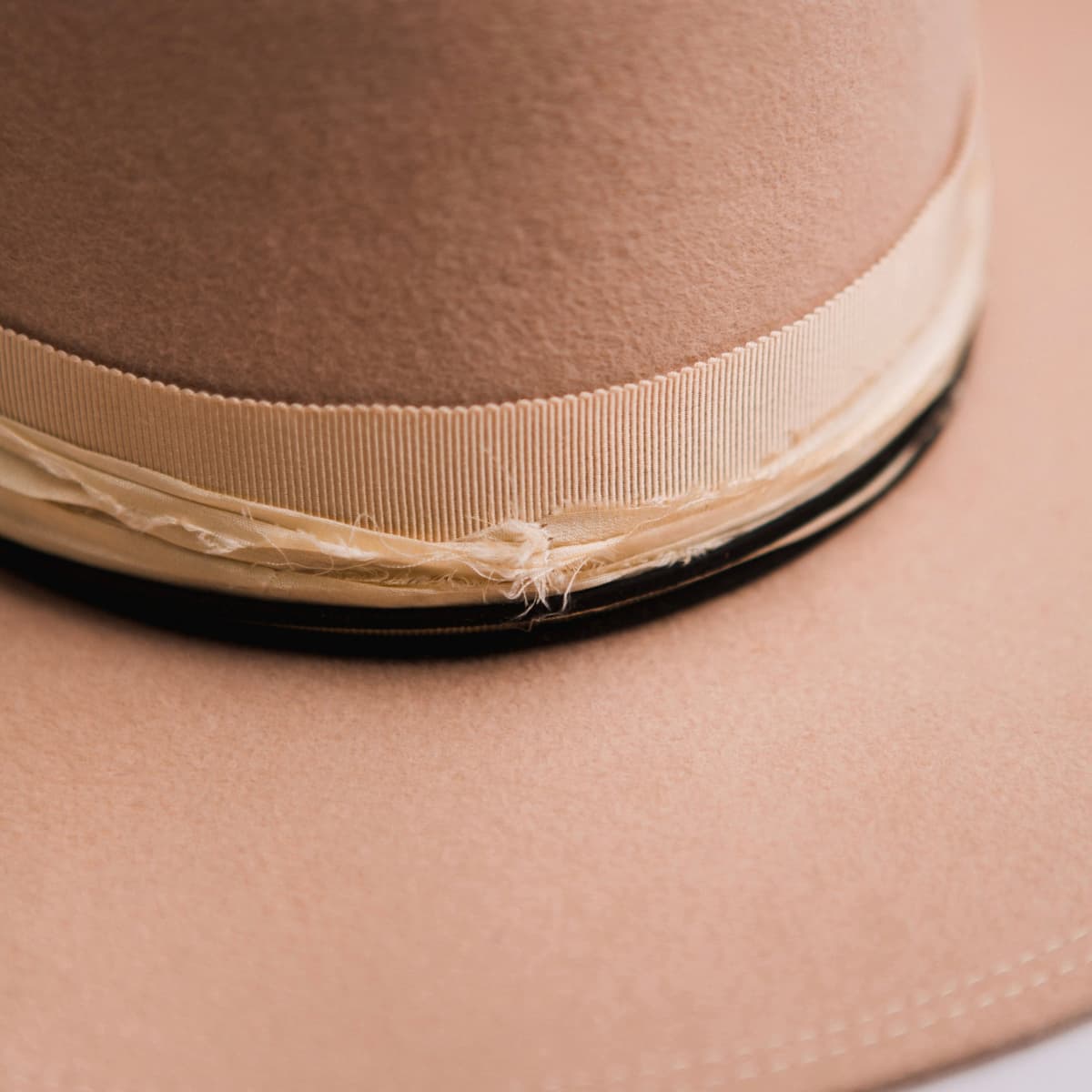 Close up detail of the Lover felt hat showing layered cream sari silk trimming and sand grosgrain band.