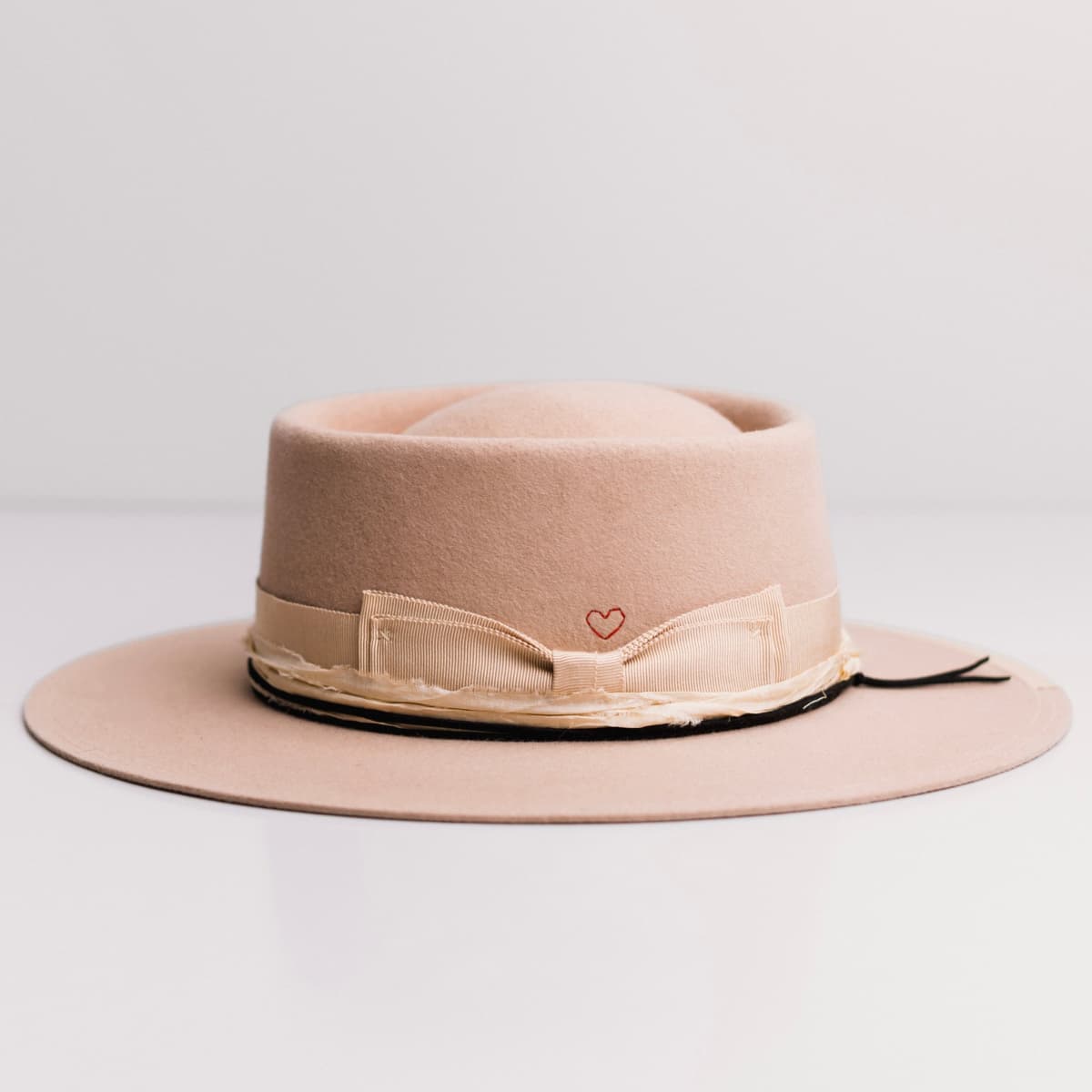 Left side view of the Lover Sand felt hat by PHYLLi Designs with black suede string and sand grosgrain brim trim.