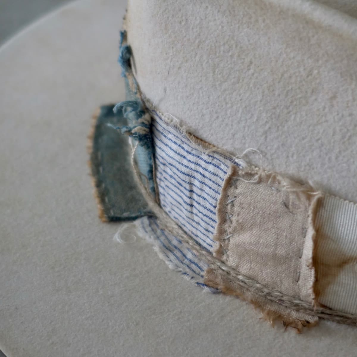 Close up detail of the Lucille Limited Edition felt hat showing striped cotton patch and hand stitching.