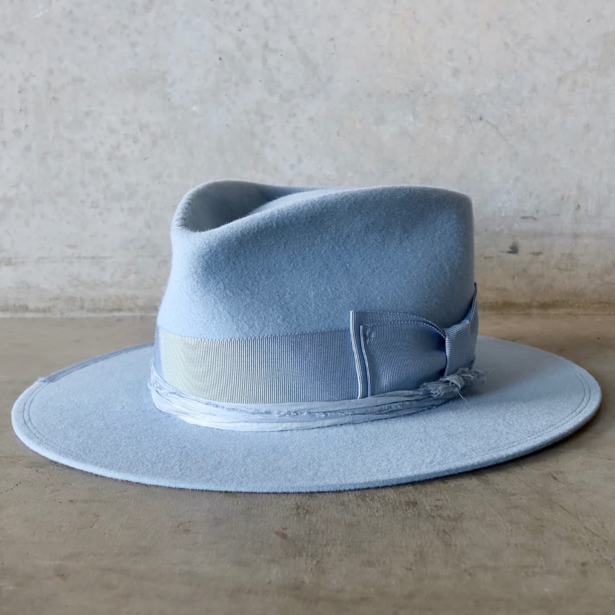 Front left angle of the Crystal Blue felt hat Lucinda by PHYLLi Designs with cornflower grosgrain bow band and tonal blue sari silk trimming.