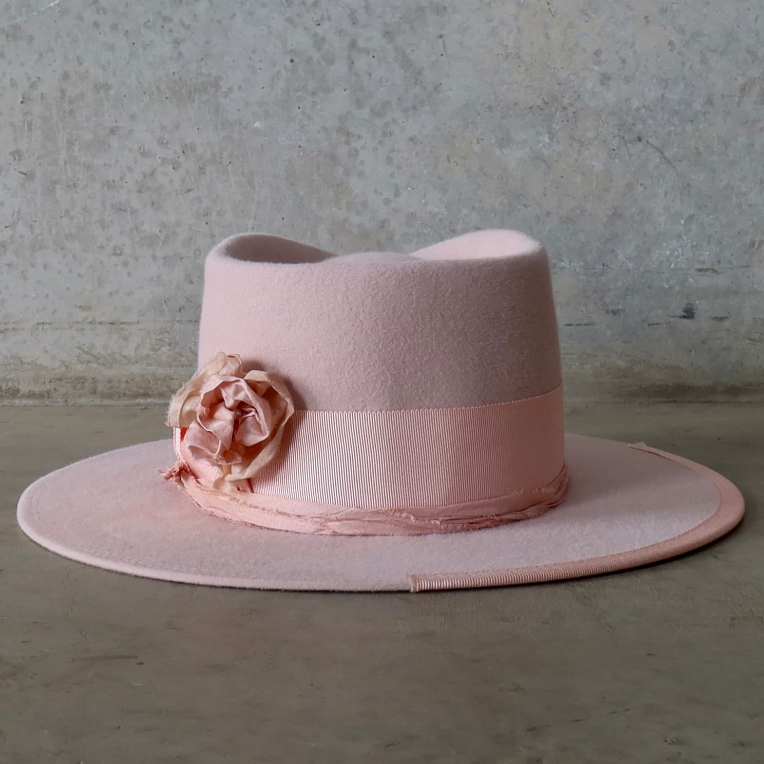Back view of the Baby Pink felt hat Lucinda Bloom by PHYLLi Designs featuring tonal sari silk trimming and salmon brim stitching.