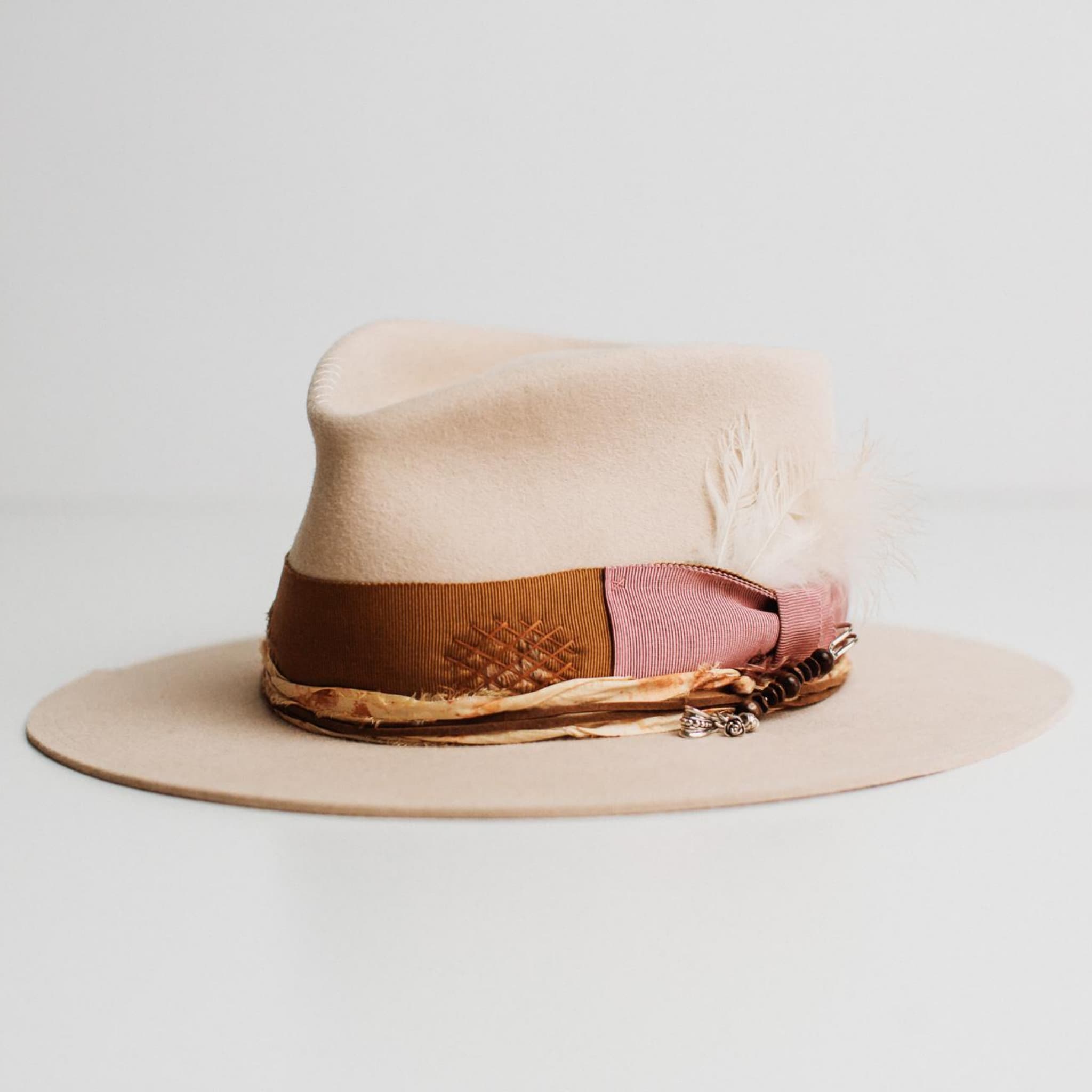 Front left angle of Malibu beige felt hat by PHYLLi Designs with copper band and ivory brim trim.