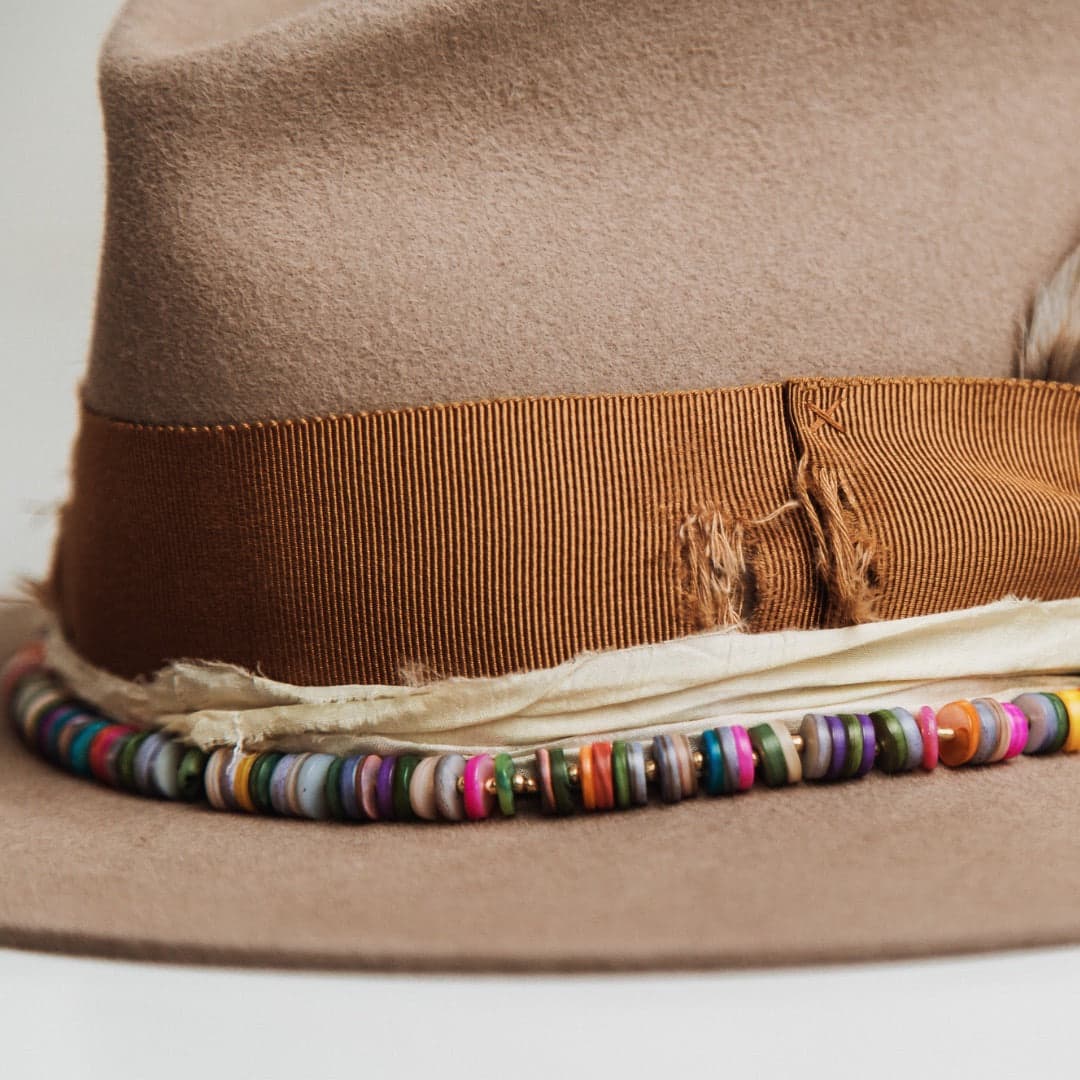 Close up detail of the Mango felt hat showing rainbow disc hat necklace and cream sari silk trim.