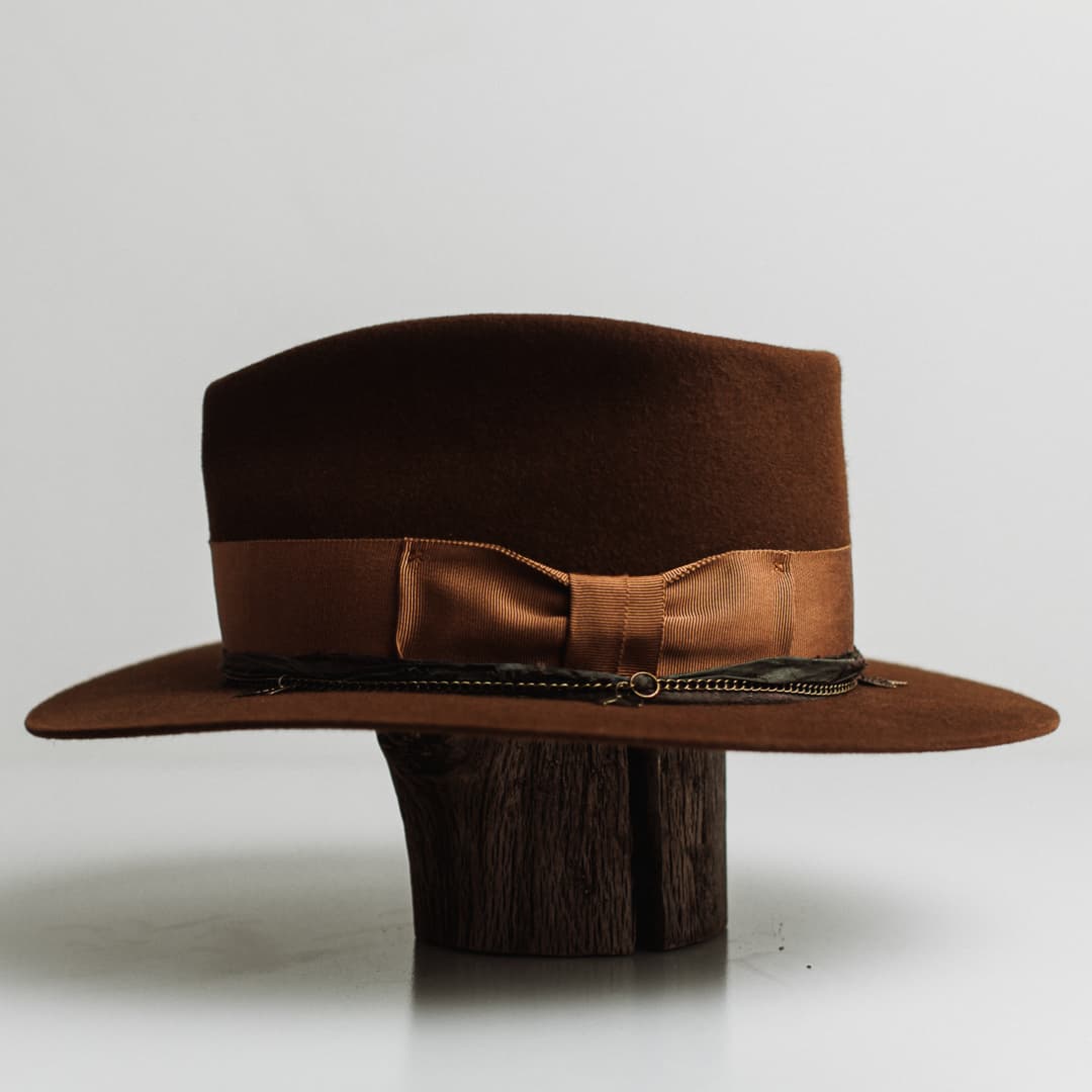 Left side view of the Maple caramel felt hat by PHYLLi Designs with copper grosgrain band and bronze crown chain with carved leaf charms.