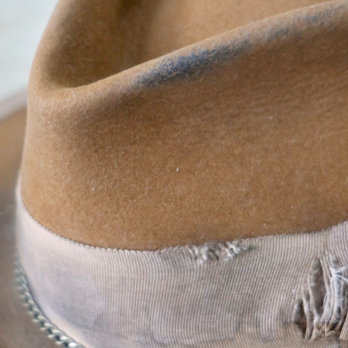 Close up detail of the Marlboro felt hat showing distressed caramel rabbit felt crown with taupe Japanese grosgrain band and bronze crown chain.