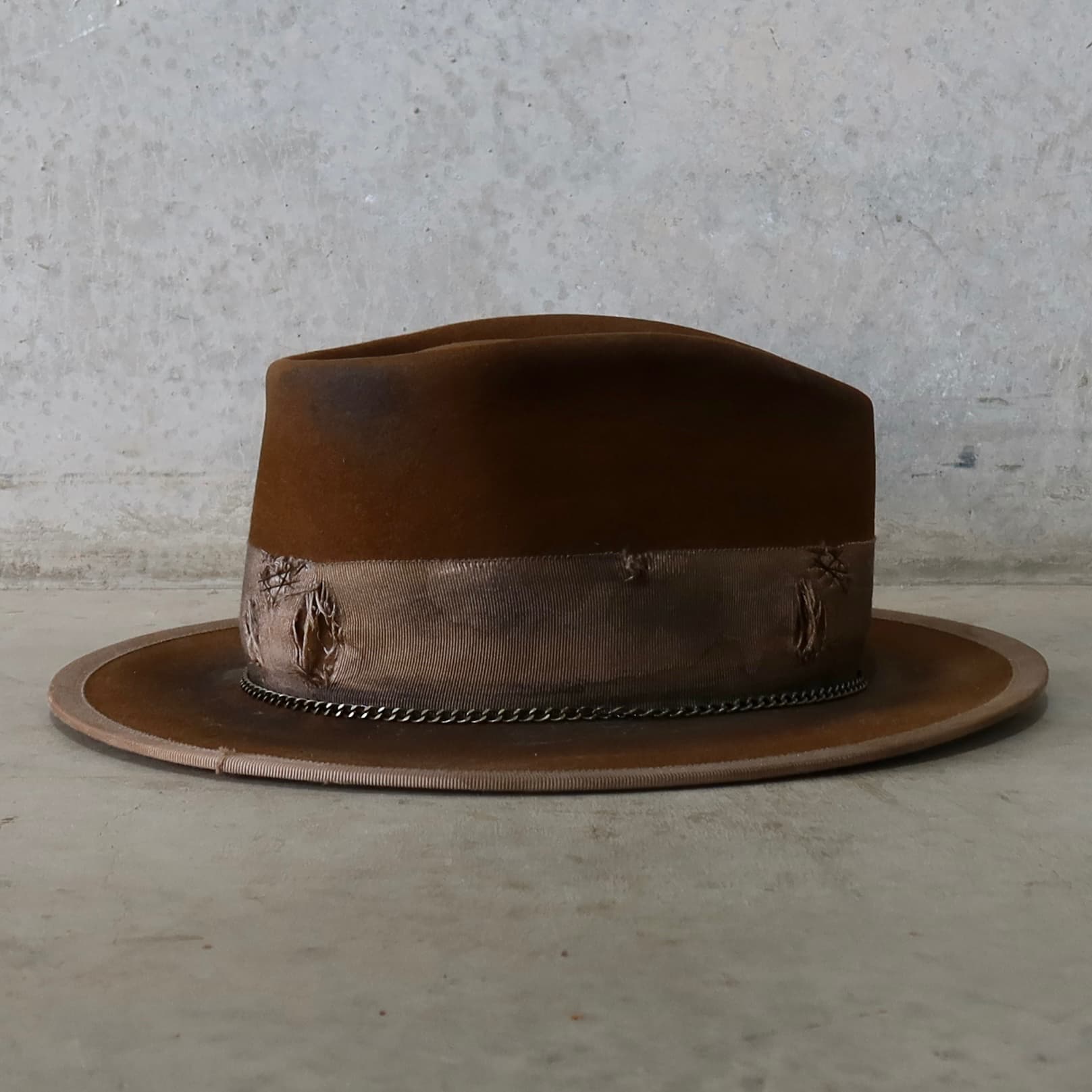 Right side view of the Marlboro Caramel distressed felt hat by PHYLLi Designs with bronze crown chain and distressed grosgrain band.