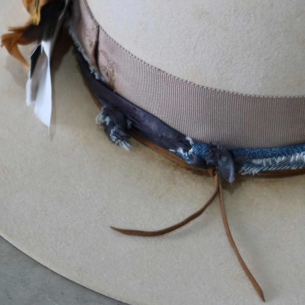 Close up detail of the McVeigh felt hat showing distressed taupe Japanese grosgrain band with frayed sari silk and denim trimming.