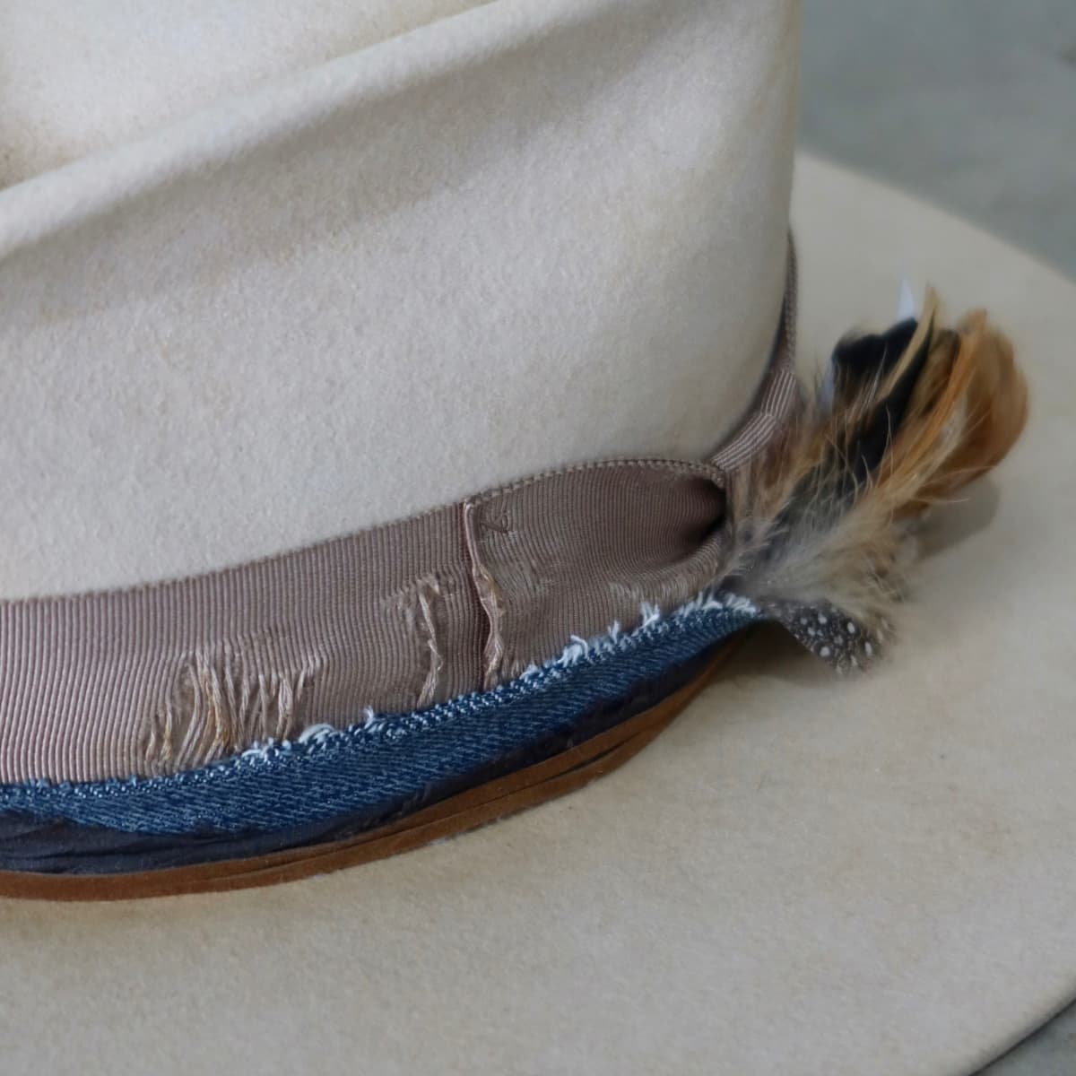 Close up detail of the McVeigh felt hat showing feather bunch with natural brown and speckled feathers tucked behind the band.