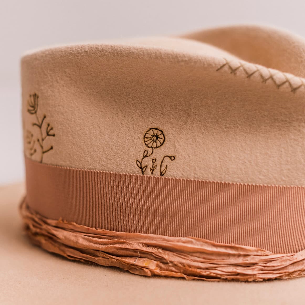 Close up detail of the Miley felt hat showing hand stitched crosses on sand western weight rabbit felt.