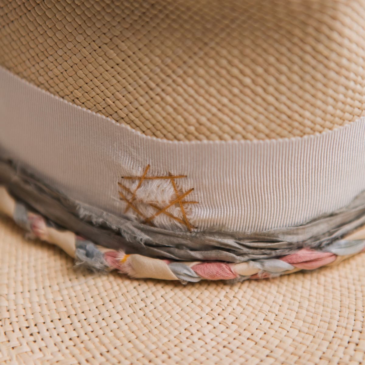 Close up detail of the My Magical Panama hat showing distressed ivory grosgrain band with darned biscuit patch and plaited sari silk trim.