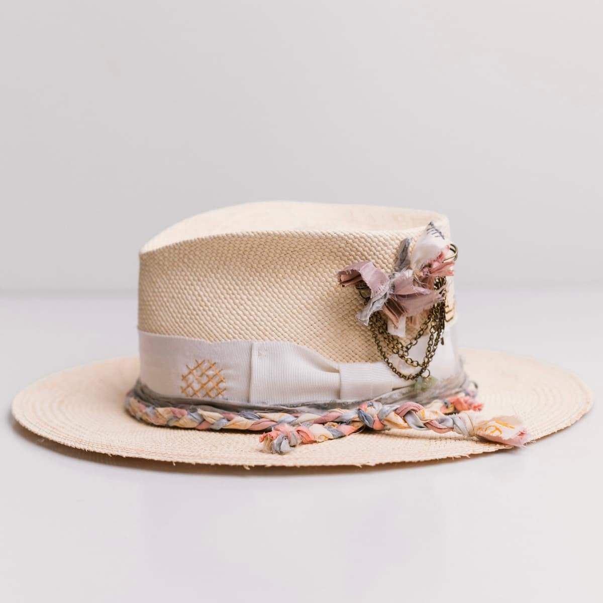 Left side view of the My Magical Natural Panama hat by PHYLLi Designs with distressed ivory Japanese grosgrain band, bronze chunky hat pin and plaited sari silk trim.