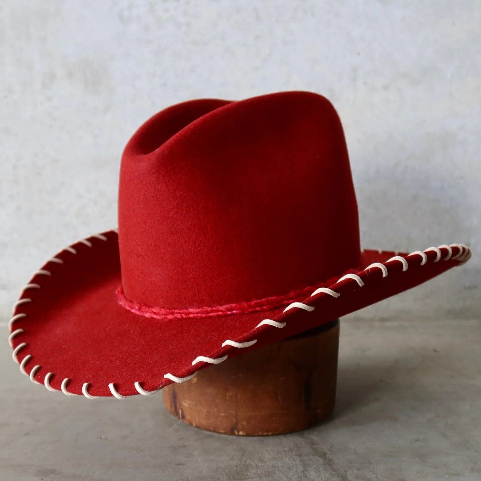 Front left angle of the spiced cherry felt cowboy hat Nevada by PHYLLi Designs with tonal red silk yarn wrap trim.