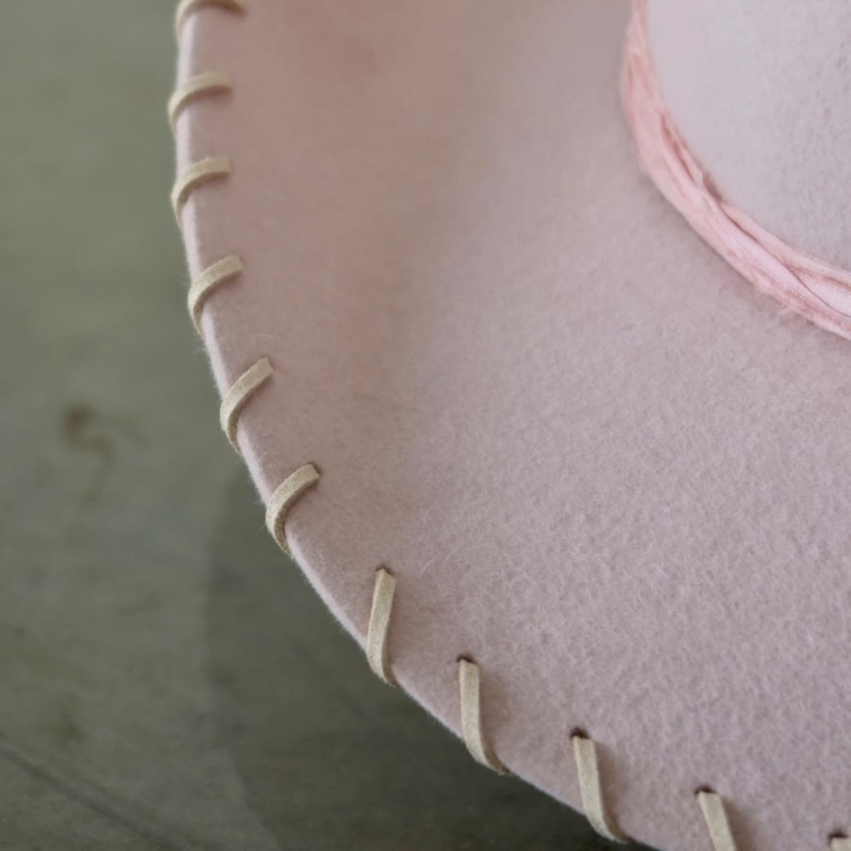 Close up detail of the Nevada cowboy hat showing nude suede brim lacing stitched around the edge of the pink felt brim.