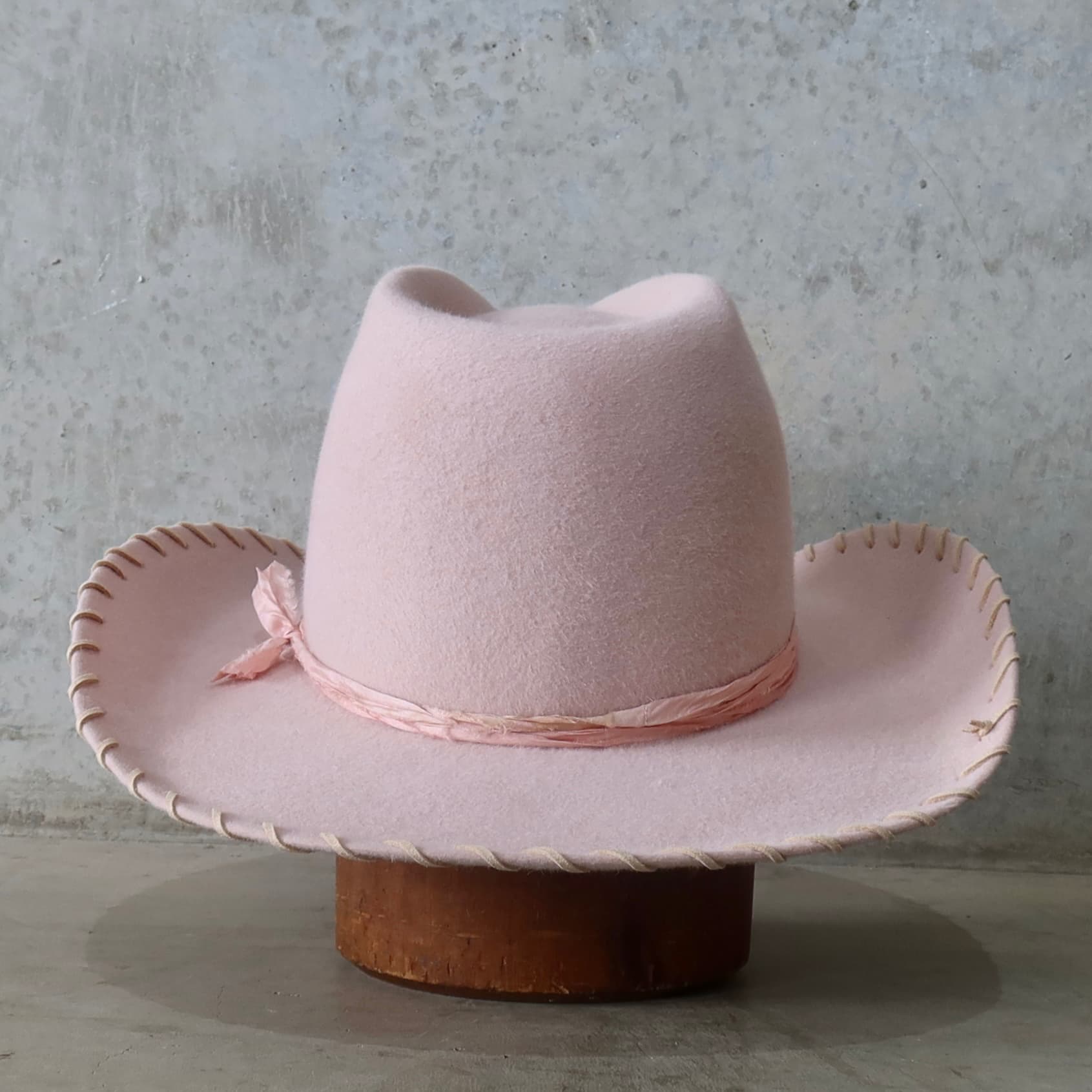 Back view of the baby pink cowboy hat Nevada by PHYLLi Designs featuring tonal pink silk yarn wraps tied at the back of the crown.