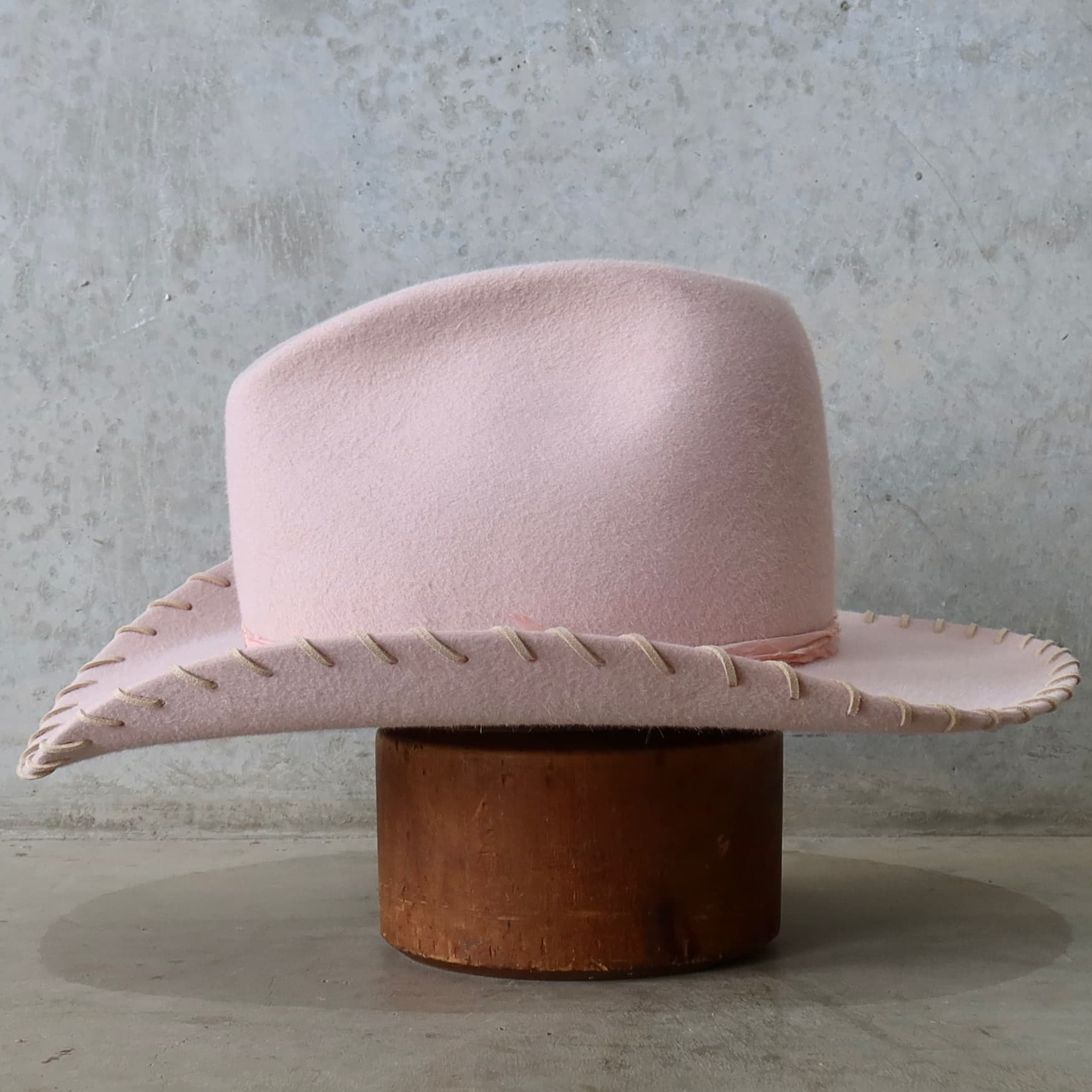 Left side view of the baby pink cowboy hat Nevada by PHYLLi Designs with tonal silk yarn wraps and nude suede brim lacing.