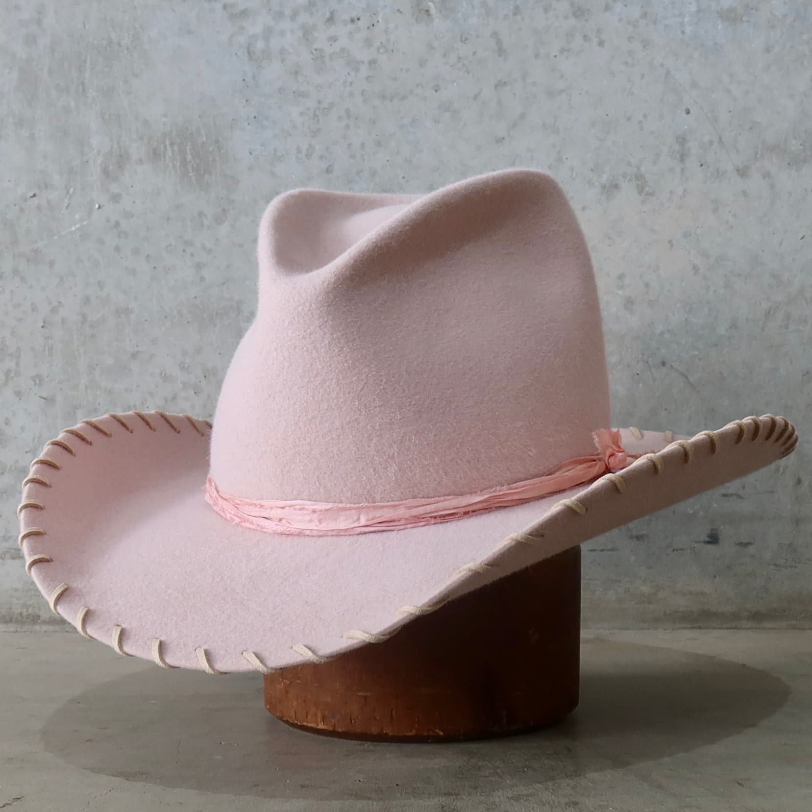 Front left angle of the baby pink cowboy hat Nevada by PHYLLi Designs with tonal pink silk yarn wraps.