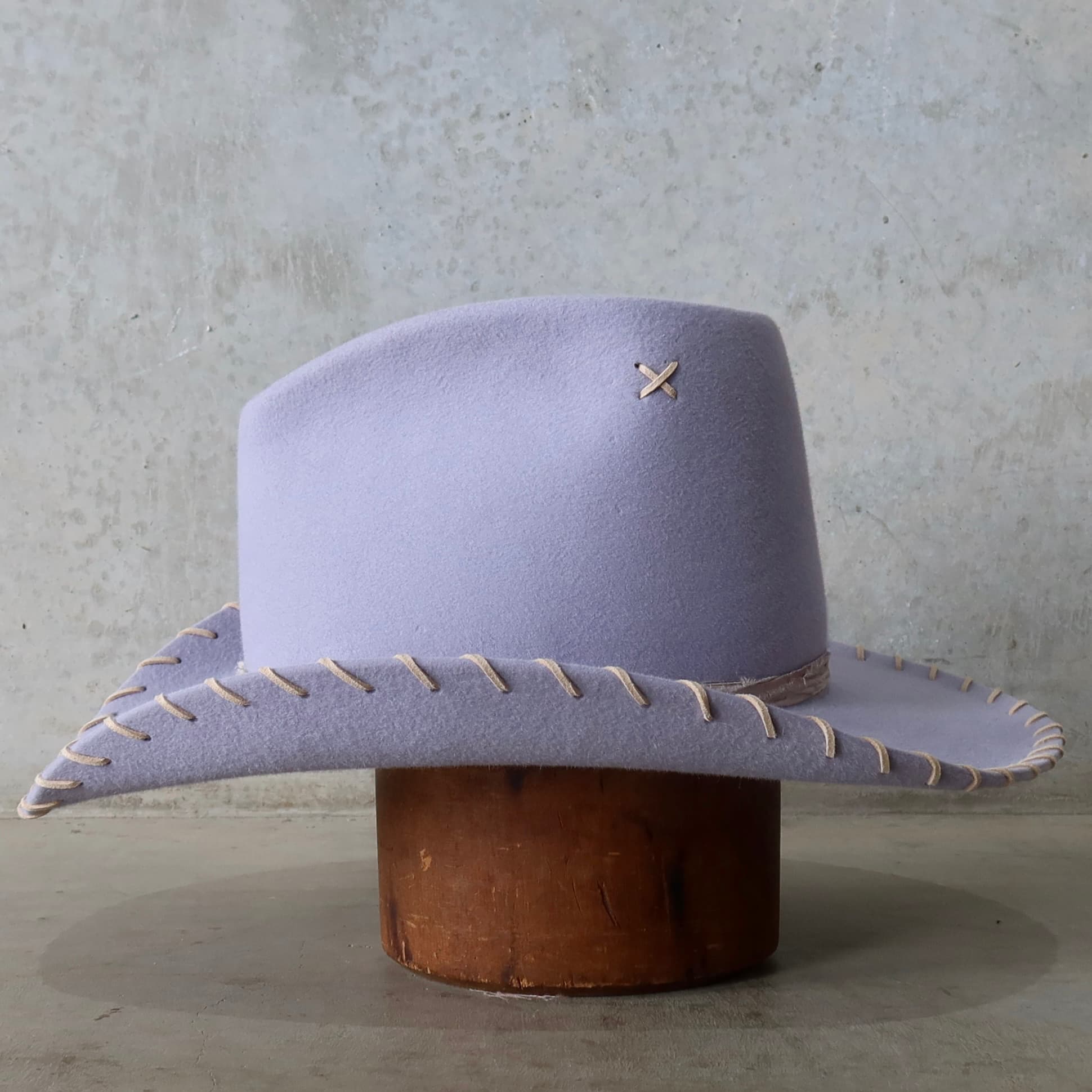 Left side view of the lilac cowboy hat Nevada by PHYLLi Designs with tonal silk yarn wraps and nude suede brim lacing.