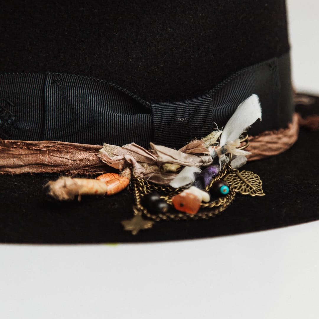 Close up detail of the Newmarket felt hat showing bronze chunky hat pin with charms, beads and sari silk tassel.