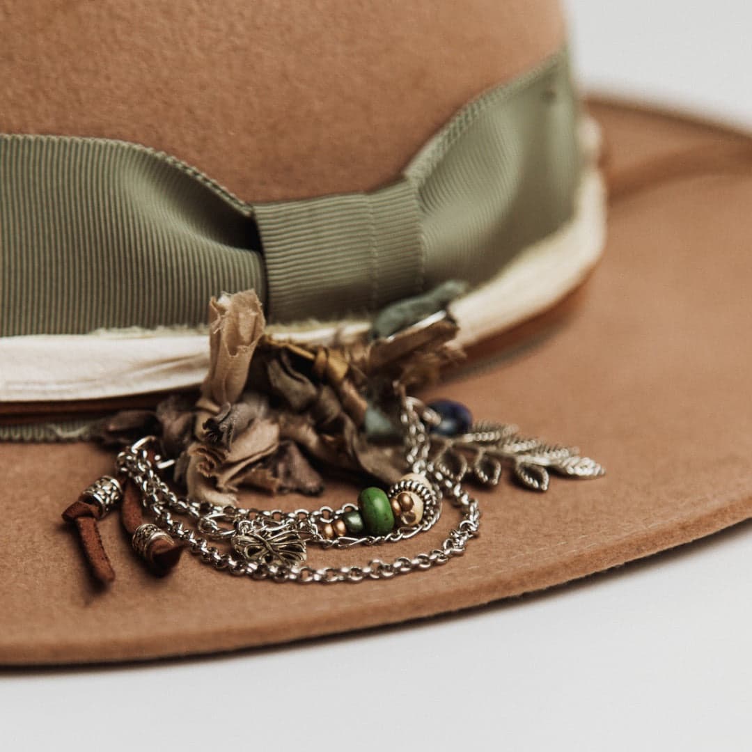 Close up detail of the Nim felt hat showing chunky silver hat pin with sari silks, tassel, charms and beads.
